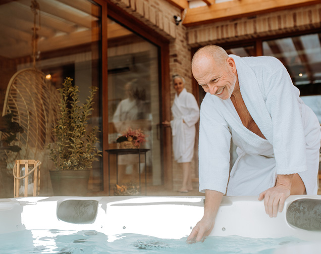 A couple relaxing beside a warm outdoor spa at dusk