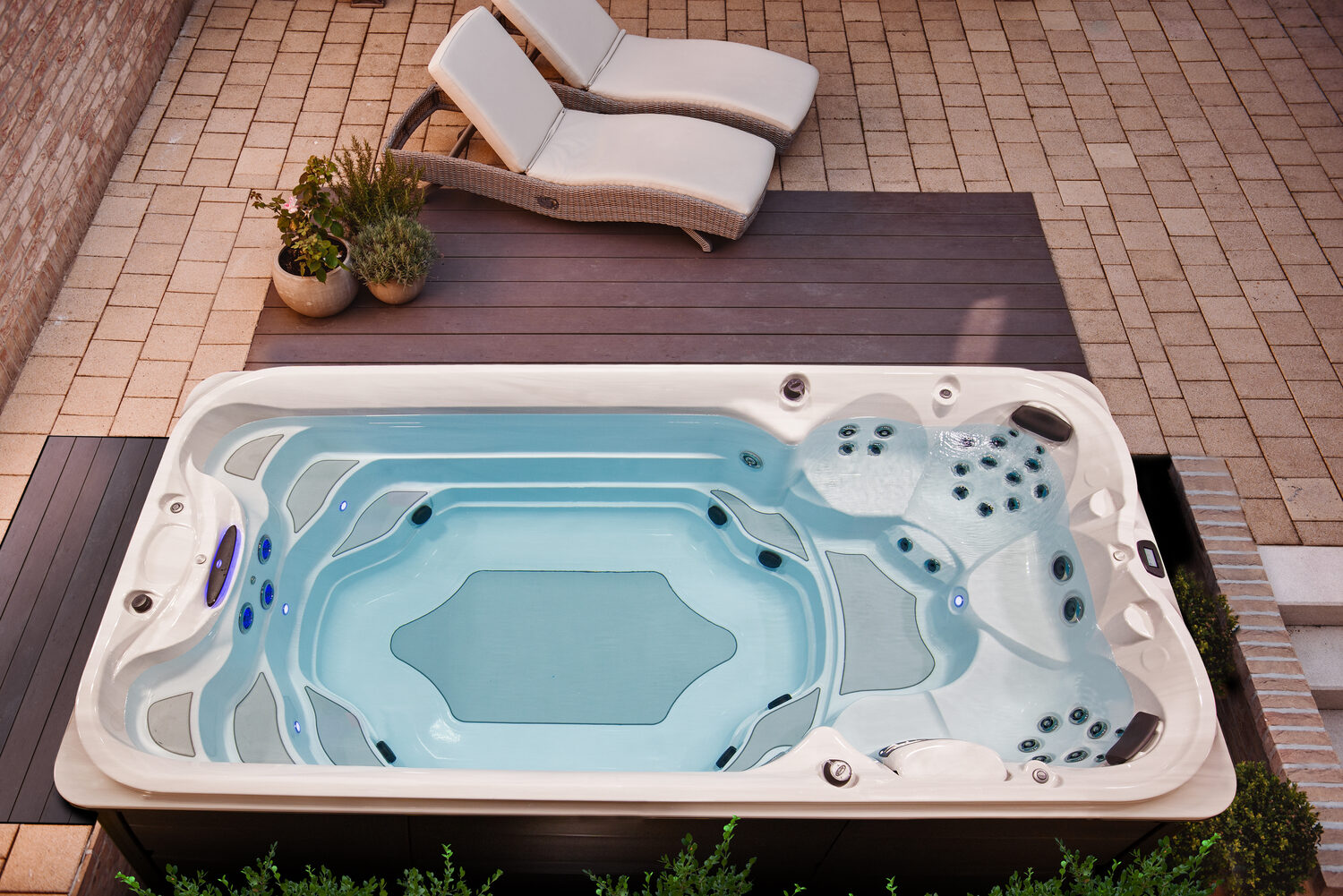 A Jacuzzi swim spa installed on a backyard patio with loungers